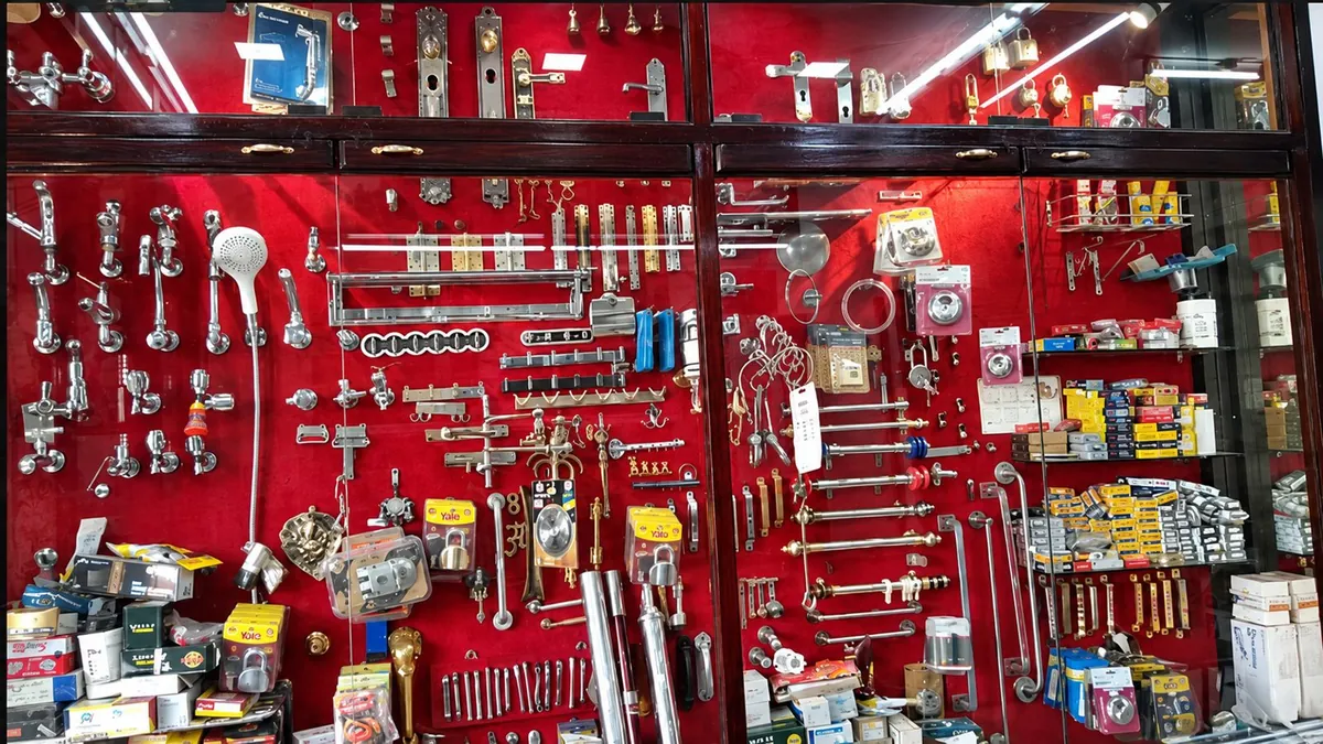 A red display wall at Chennai Traders filled with taps, rods and bathroom fittings